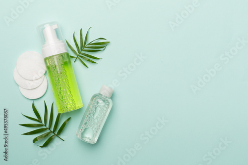 Foaming facial cleanser and micellar water on color background, top view photo