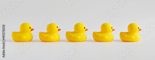 Fotografie Yellow rubber ducks arranged in a row on white background