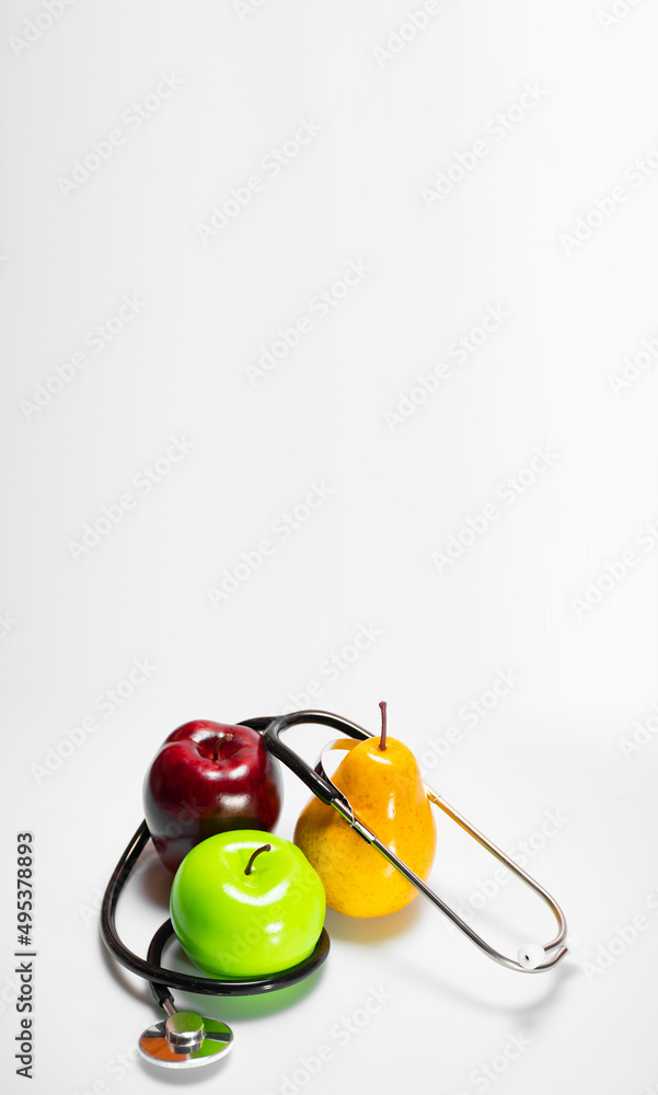Healthy snack: green apple, ripe pear and red apple and a stethoscope or phonendoscope, diet and sports on white background with place for text. Concept of healthy lifestyle, vertical banner Healthy snack: green apple, ripe pear and red apple and a stethoscope or phonendoscope, diet and sports on white background with place for text. Concept of healthy lifestyle, vertical banner