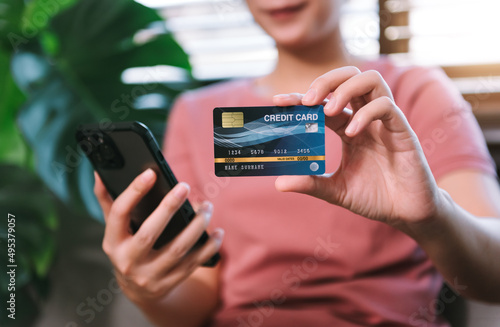 Asian young woman housewife using smartphone for online shopping and paying with credit card for shopping housework equipment.