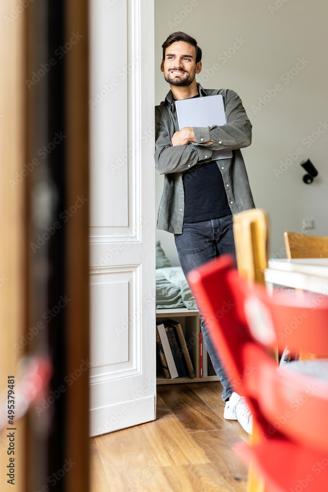 Young man holding tablet PC leaning on door Young man holding tablet PC leaning on door