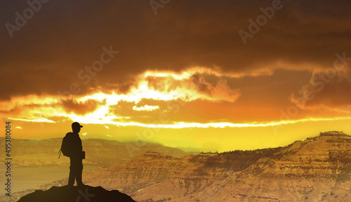 Success achievement concept. Silhouette of person standing on top of mountain.