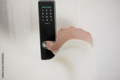 Woman unlocking smart door of house with fingerprint photo