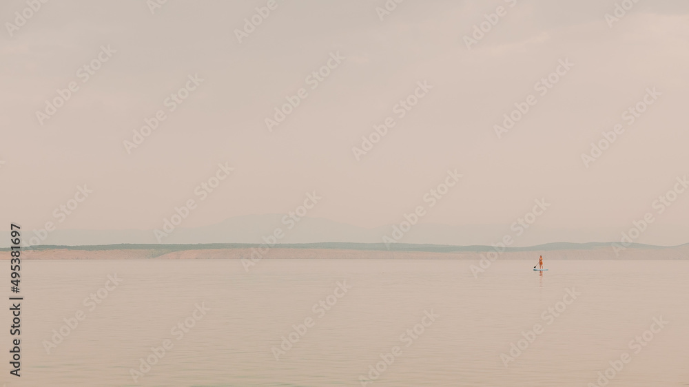 Unrecognizable woman stand-up paddle boarding at sea in sunrise, sport and recreational activity Unrecognizable woman stand-up paddle boarding at sea in sunrise, sport and recreational activity
