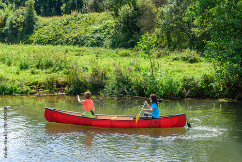 Zwei Frauen paddeln entspannt in einem Kanu in einer idyllischen Fluusslandschaft