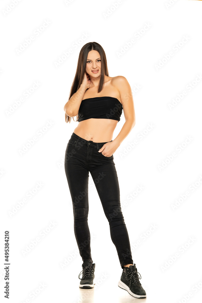 Front view of a young smiling woman in black jeans and short top posing on a white background Front view of a young smiling woman in black jeans and short top posing on a white background