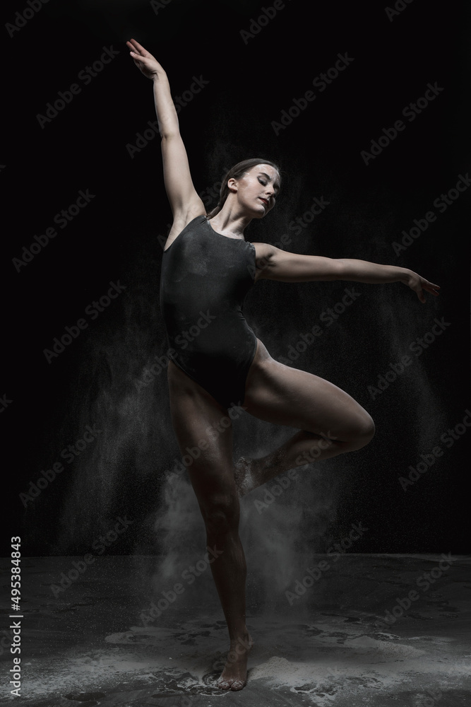 Chica joven bailando en movimiento con polvos de harina en dispersión con fondo oscuro. 
Baile y danza artística. 