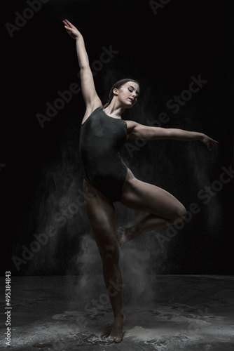 Chica joven bailando en movimiento con polvos de harina en dispersión con fondo oscuro.  Baile y danza artística.  © Sinu Mora