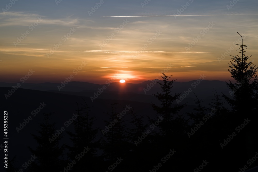 Sunrise in the mountains. In the foreground silhouettes of trees. Beautifully colored sky. Central Europe, Czech Republic, Lysá Hora.