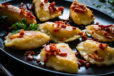 Dumplings - cheese noodles with onion and bacon on black wooden table
