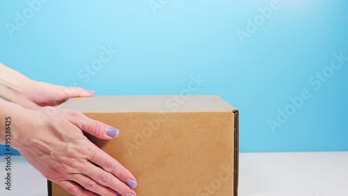 The seller deliver cardboard box to buyer, close-up, side view. Pickup service job from online shop store e-commerce with omni channel fast express post. Blue wall and white table.