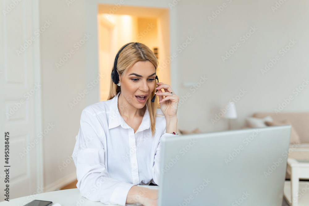 Happy young woman working on laptop while talking to customer on phone. Consulting corporate client in conversation with customer using computer. Service desk consultant talking in a call center.
