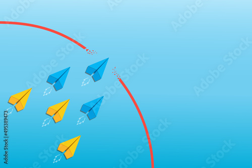 Concept of overcoming barriers on the way to goal with blue, yellow paper plane breaking through obstacle on blue background. Deal with difficulties on the way to target.