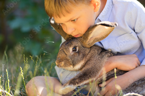 the boy lies on the green grass holds hugs the rabbit, holiday with the rabbit
