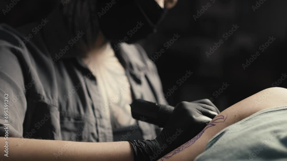 Caucasian woman in face mask tattooing arms of her customer. Shot with RED helium camera in 8K. Caucasian woman in face mask tattooing arms of her customer. Shot with RED helium camera in 8K.