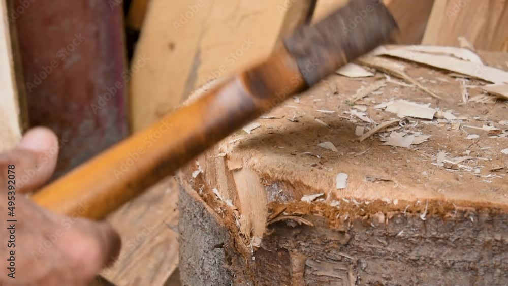 Man splits and cuts small pieces of wood on a stump with an axe Man splits and cuts small pieces of wood on a stump with an axe