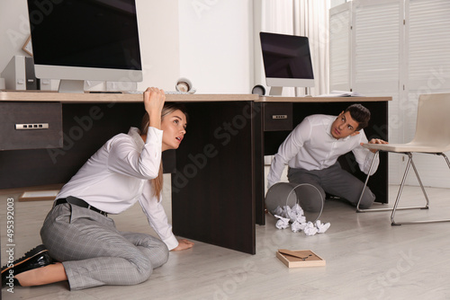 Scared employees hiding under office desks during earthquake photo