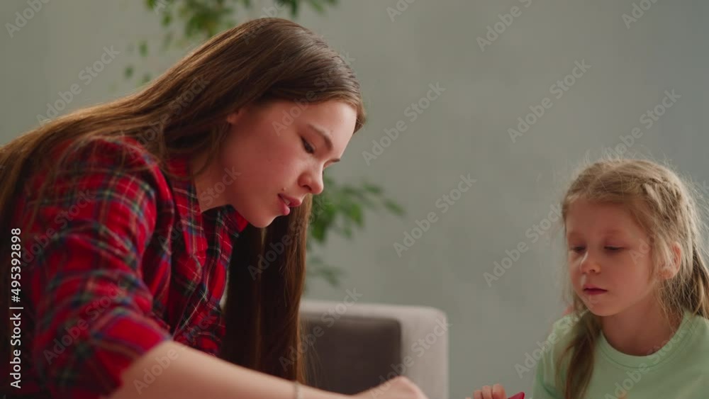 Concentrated little girl looks at long haired sister mixing colors with comb for Ebru art at home slow motion. Traditional Turkish design practicing Concentrated little girl looks at long haired sister mixing colors with comb for Ebru art at home slow motion. Traditional Turkish design practicing