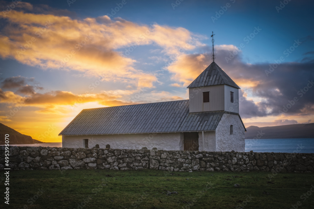 Stunning autumn view of medieval Olaf's Church in Kirkjubour village. Great sunrise in Faroe Islands, Denmark, Europe. Calm morning scene of Hestur Island. Traveling concept background. November 2021