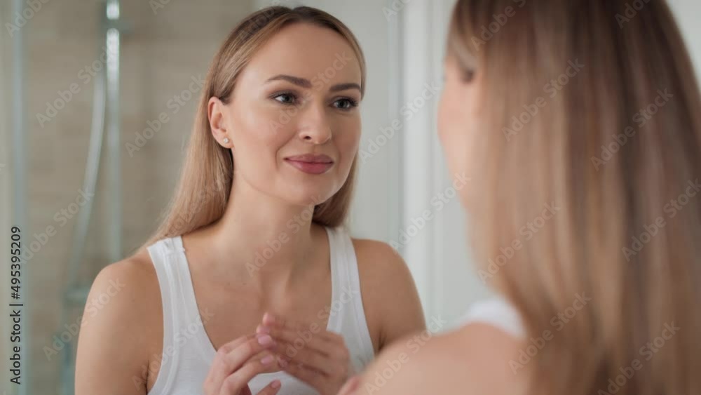 Young woman looking at herself in the mirror in the morning. Shot with RED helium camera in 8K.