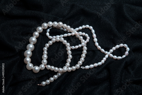 White pearls on the black shiny fabric background