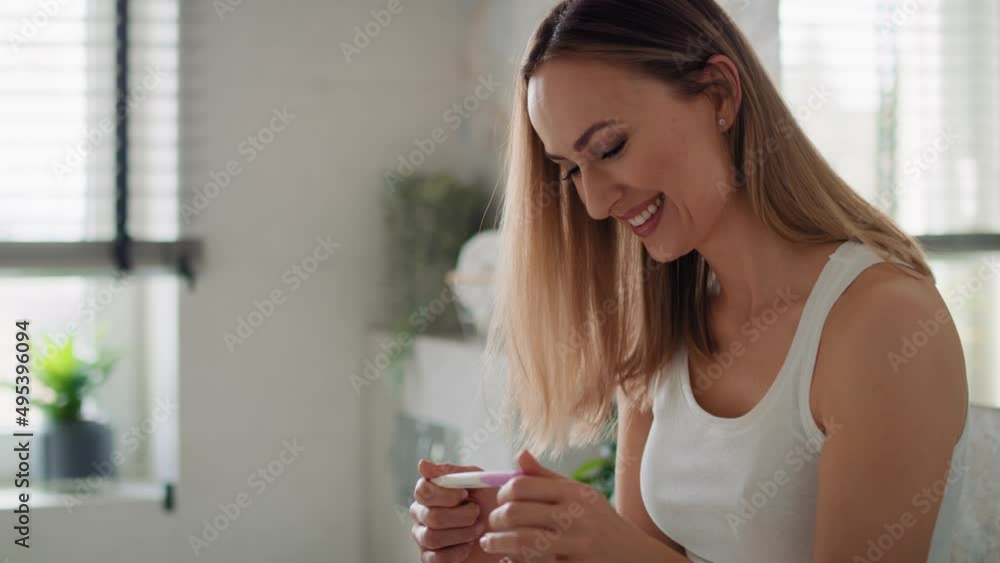 Cheerful woman standing and holding a pregnancy test. Shot with RED helium camera in 8K. Cheerful woman standing and holding a pregnancy test. Shot with RED helium camera in 8K.