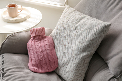 Canvas Print Hot water bottle with knitted cover and cushion on armchair indoors