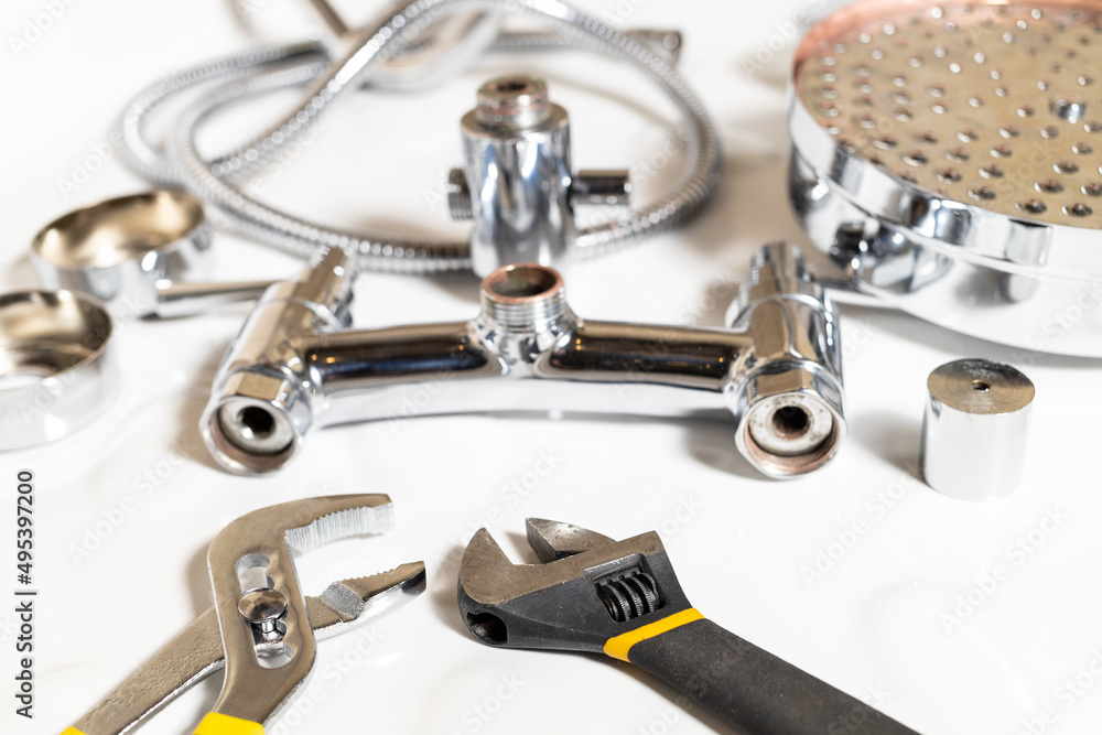 wrenches closeup and disassembled shower faucet on white ceramic shower tray wrenches closeup and disassembled shower faucet on white ceramic shower tray