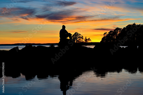 Man sitting overlooking sunset over lake Vattern