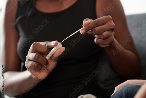 Closeup image of woman putting swab with nasal musuc in liquid for test cassette