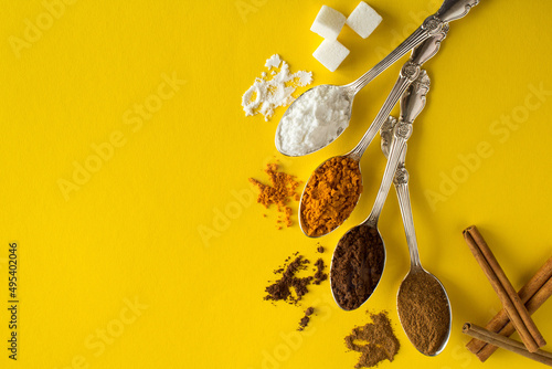 Spice in the silver spoons on the yellow background. Top view. Copy space.