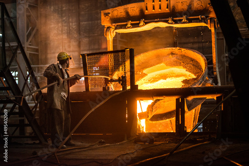 Steelworker at work near the tanks with hot metal photo