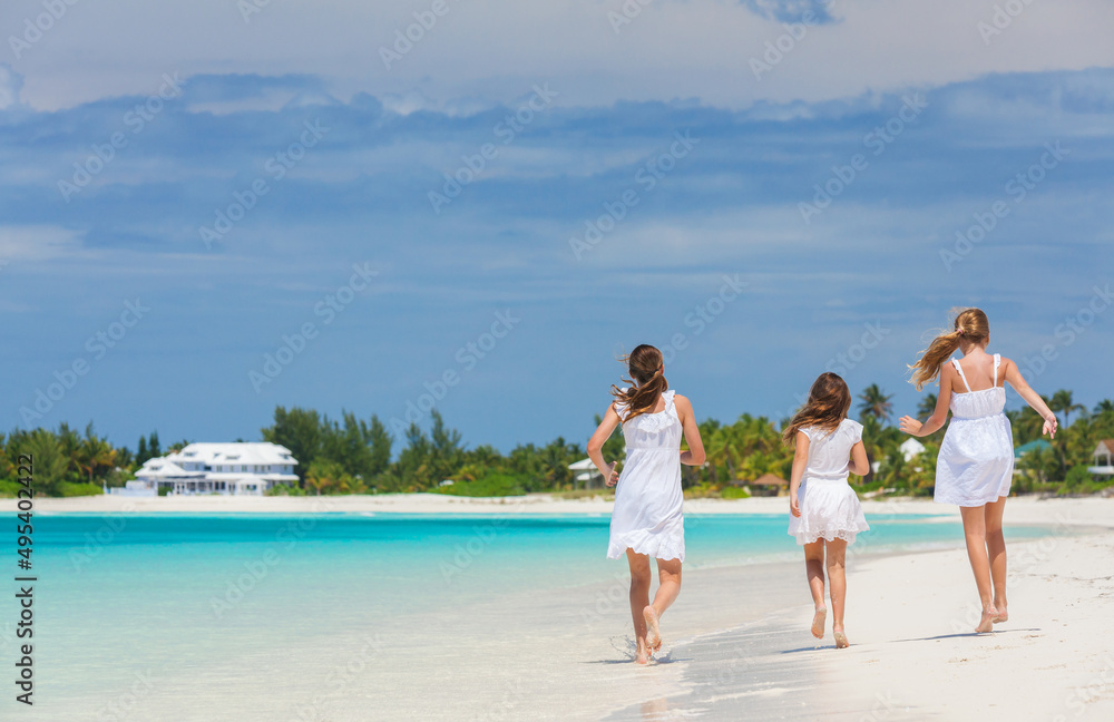 Healthy young Caucasian siblings walking along Caribbean beach