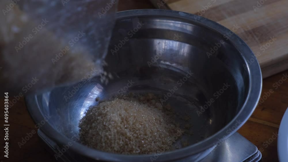Pouring Brown Sugar Into Stainless Bowl For Baking. close up Pouring Brown Sugar Into Stainless Bowl For Baking. close up