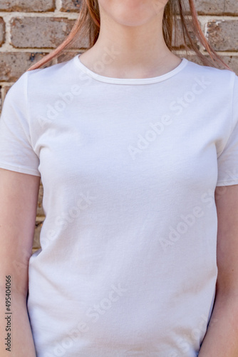 Girl wearing mockup white t-shirt on brick wall background. Template copy space
