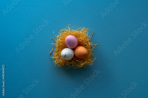 Nest with Easter eggs on blue background with copy space for text.