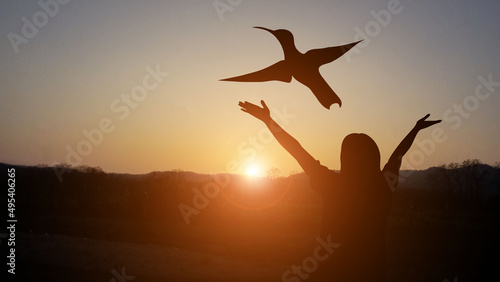 A man with a cross at sunset, a golden light beneath a flying bird, indicates the joy of freedom and freedom in the midst of nature in the evening.