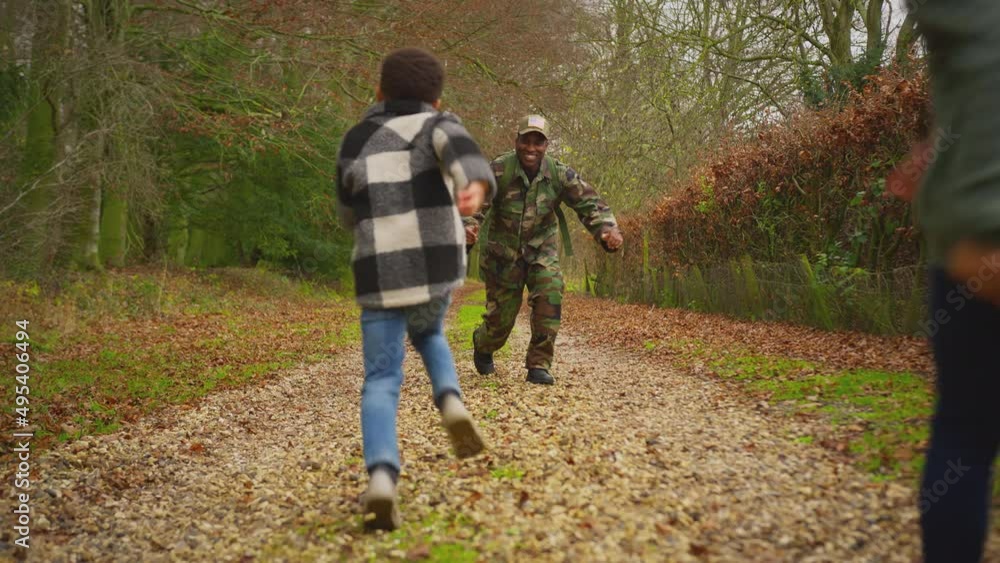 American soldier coming home on leave kneels to meet son and daughter who run to greet him outdoors - shot in slow motion American soldier coming home on leave kneels to meet son and daughter who run to greet him outdoors - shot in slow motion