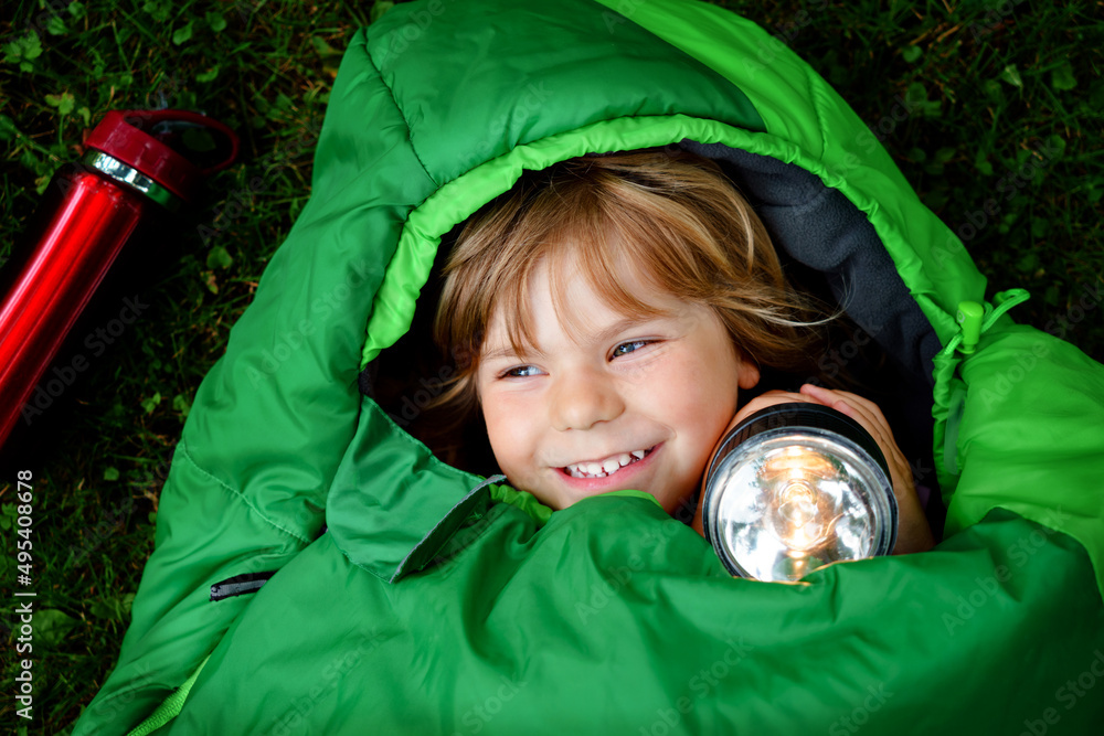 Preschool little girl in sleeping bag camping. Outdoors activity with