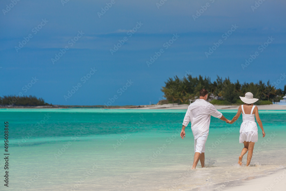 American Caucasian couple walking on a beach together American Caucasian couple walking on a beach together