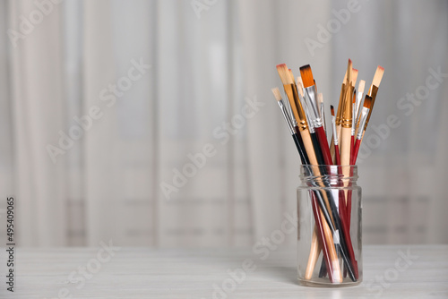 Many different paintbrushes on white wooden table indoors, space for text