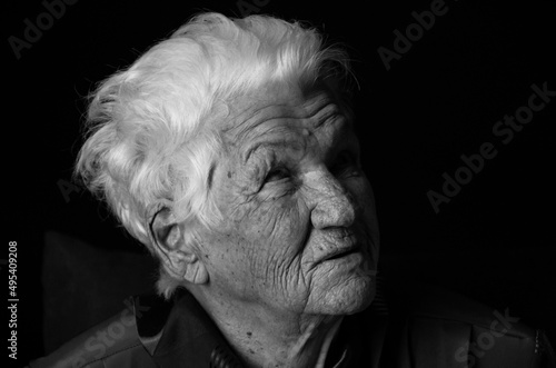 Portrait of serious senior woman against black background. Black and white photo.