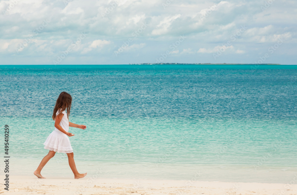 Healthy young Caucasian girl walking along Caribbean beach