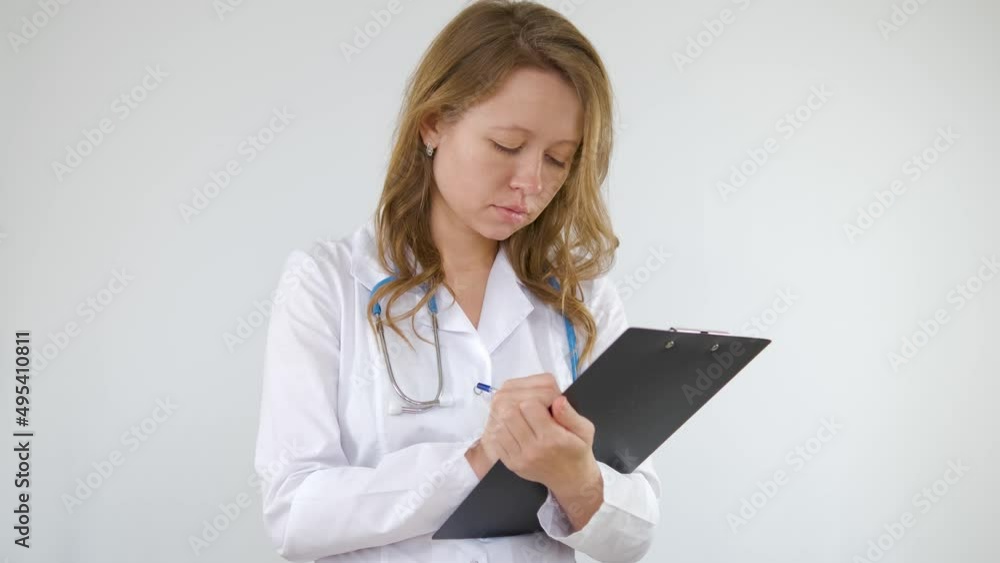 A doctor in a medical gown fills out paperwork on a tablet. Girl on a white background A doctor in a medical gown fills out paperwork on a tablet. Girl on a white background