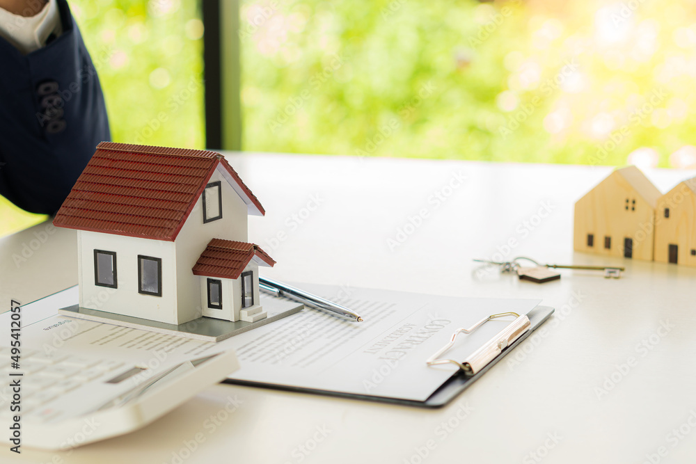 Real estate office home sales agents work with contract documents with house designs and calculators on the table. Real estate office home sales agents work with contract documents with house designs and calculators on the table.