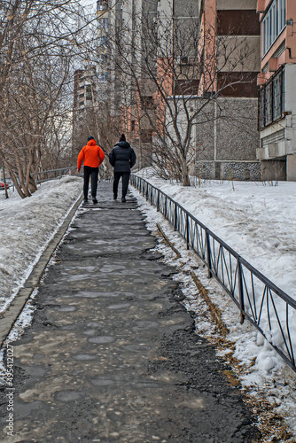 Two young men walk along the sidewalk on a spring day