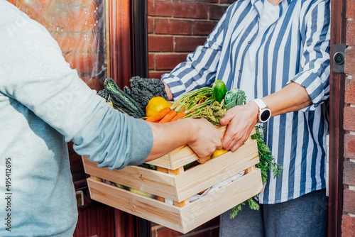 Home fresh food delivery. Woman taking wooden box with vegetables and fruits. Support local farmer food production . New Start of a healthy life, weight loss concept. Online food order. Recipe box photo
