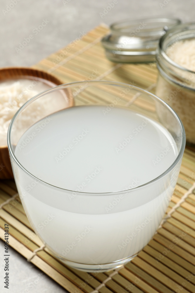 Glass with natural rice water on bamboo mat, closeup Glass with natural rice water on bamboo mat, closeup