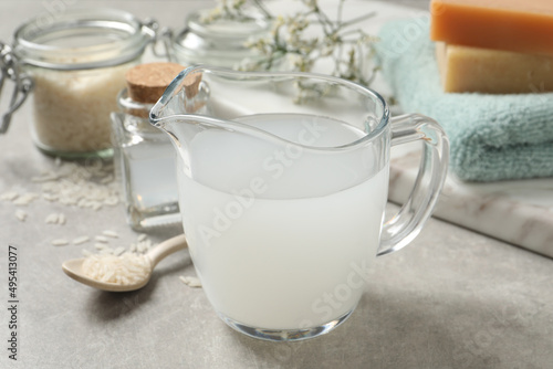 Glass jug with natural rice water on light grey table