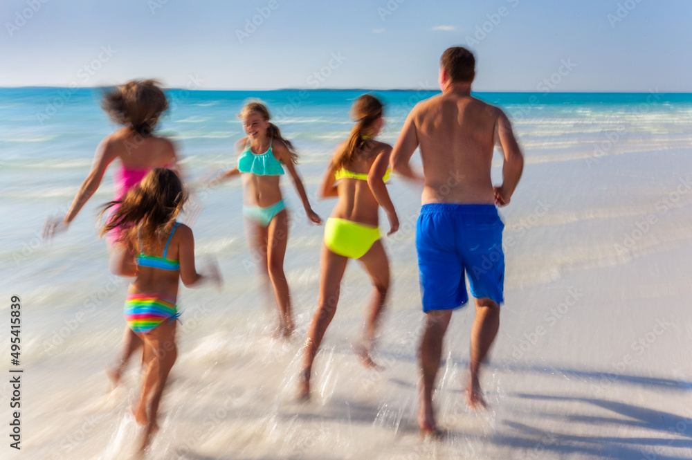 Young family enjoying leisure walking on tropical beach